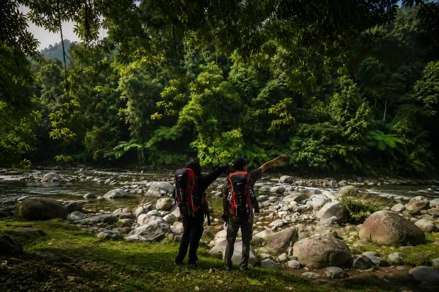 Dua pendaki menjelajah tepi sungai di alam Sumatera Barat